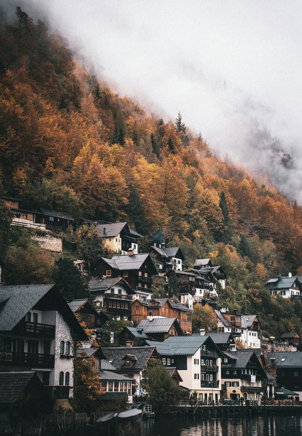 Villaggio tradizionale su una collina riflesso in un lago calmo in autunno.