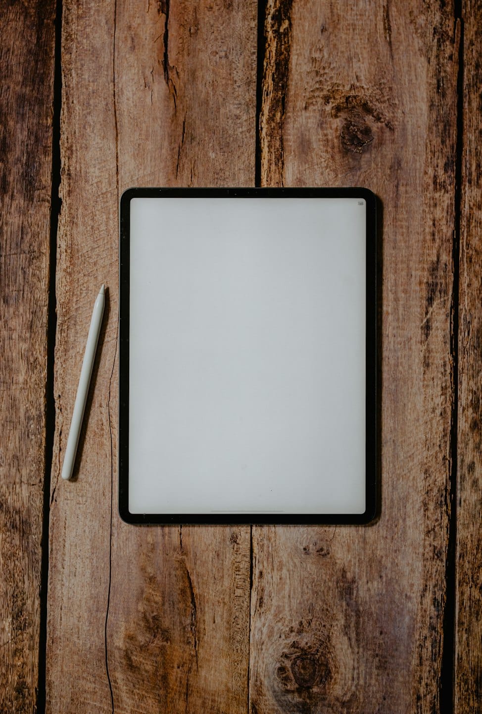 Un tablet digitale e uno stilo su un tavolo di legno.